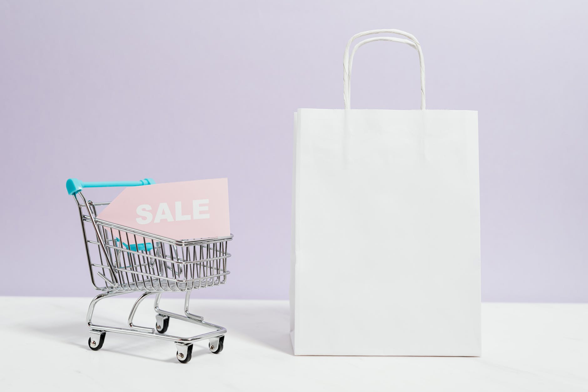 sale sign in a miniature shopping cart and paper bag